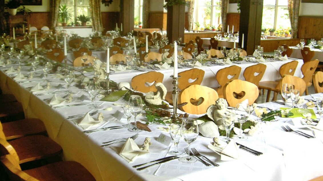 Ein eleganter Festsaal mit einem langen Tisch, der reich gedeckt ist. Das Ambiente ist freundlich mit Dekorationen und Kerzen. | © Steinegger