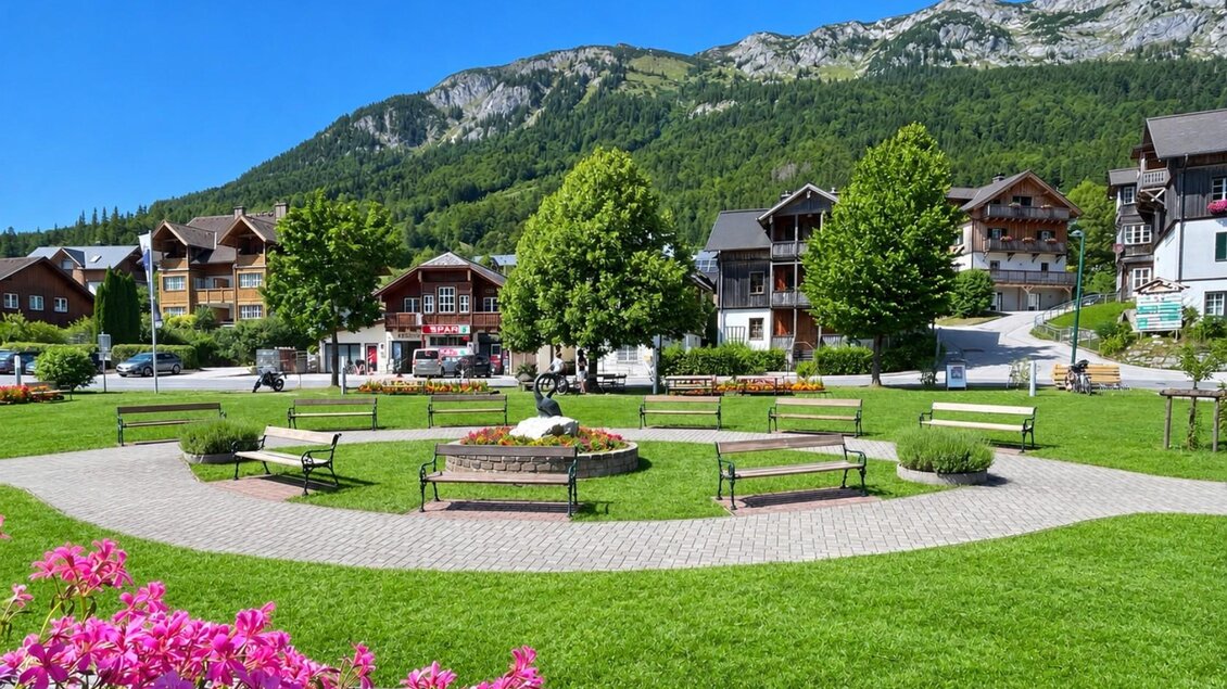 <p>Der idyllische Gemeindepark in Grundlsee mit saftig grünem Rasen, gemütlichen Bänken und bunten Blumen. Im Hintergrund eröffnet sich der Blick auf die malerische Bergwelt des Ausseerlandes und die traditionellen Häuser von Grundlsee.</p> | © Tourismusverband Ausseerland