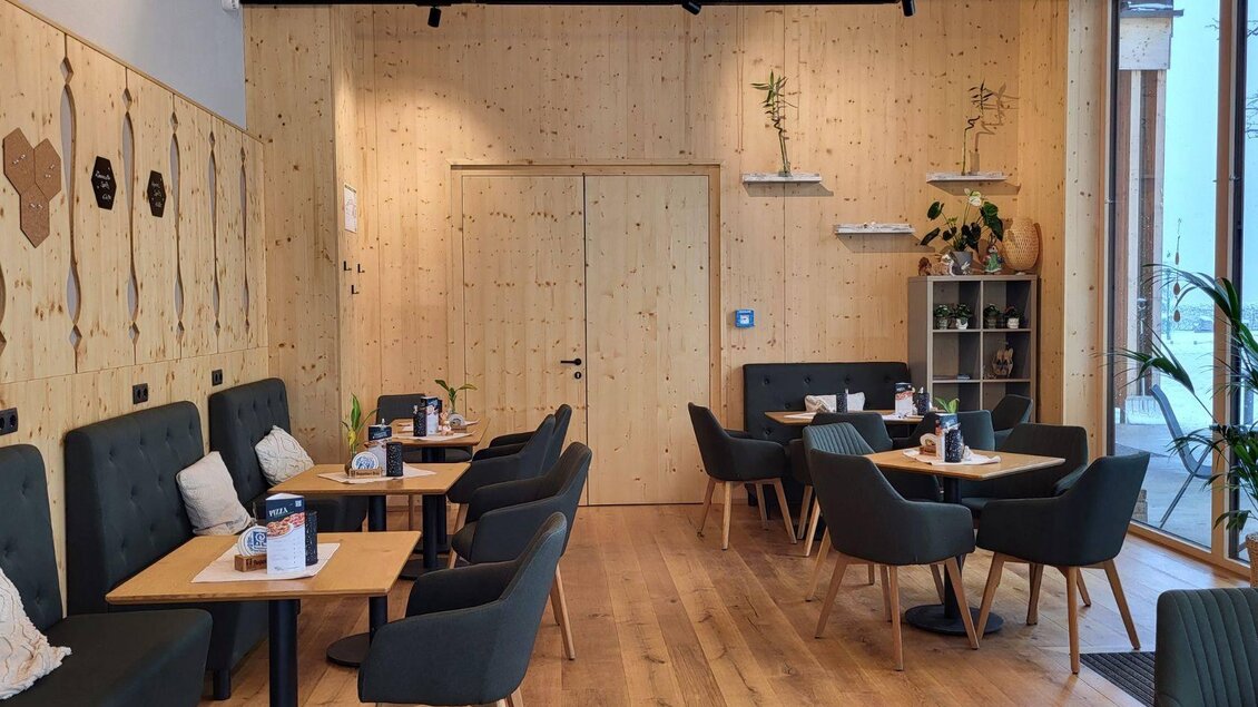 Ein modernes Café mit Holzverkleidung und einer gemütlichen Atmosphäre. Die Einrichtung umfasst stilvolle Tische und Stühle sowie Pflanzen für eine einladende Note. | © Petra Kirchschlager