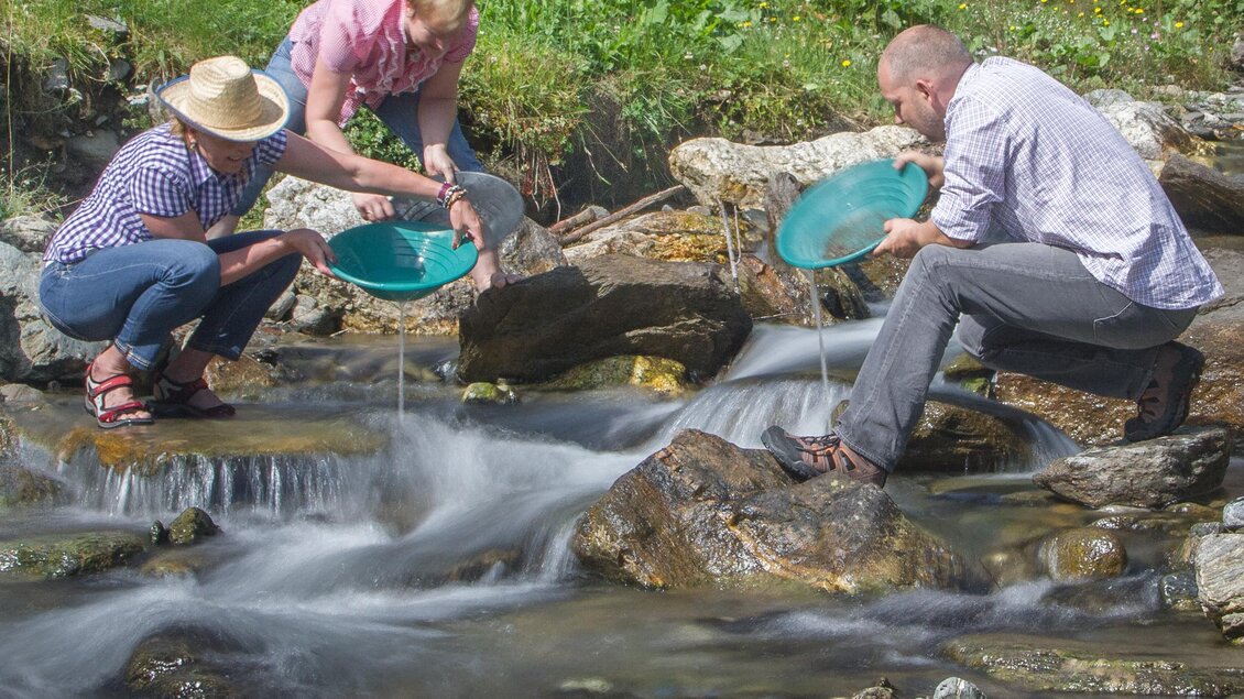 Drei Personen stehen an einem fließenden Gewässer und suchen nach Gold. Sie benutzen spezielle Schalen, um das Wasser zu filtern und ihre Funde zu überprüfen. | © Erlebnisregion Murtal