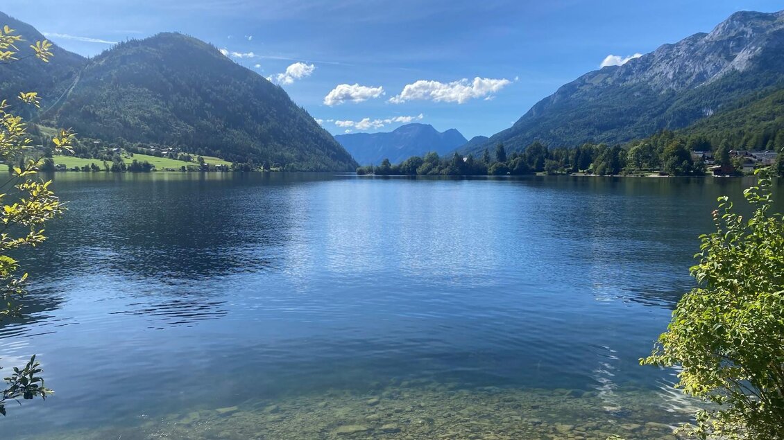 Ein ruhiger See umgeben von Bergen und Bäumen. Der Himmel ist klar und blau, und das Wasser spiegelt die wunderschöne Landschaft wider. | © Bettina Scheck