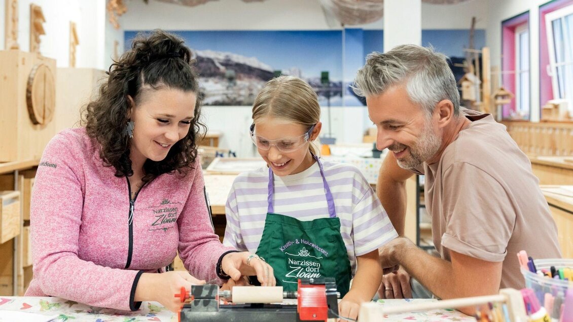 Drei Personen arbeiten gemeinsam an einem kreativen Projekt in einem hellen Bastelraum. Die Atmosphäre ist freundlich und einladend. | © www.zloam.at