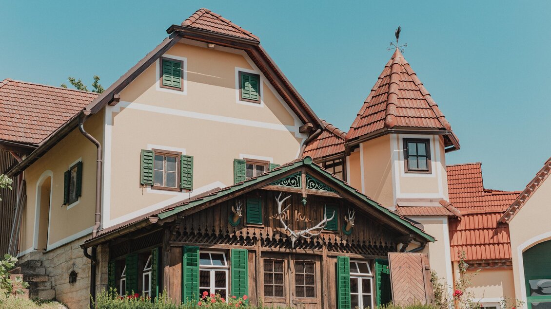 Traditionelles Gebäude des Weinguts Hutter in Feldbach mit grünen Fensterläden, roten Ziegeldächern und rustikaler Holzfassade im Thermen- & Vulkanland in der Steiermark. | © Thermen- & Vulkanland
