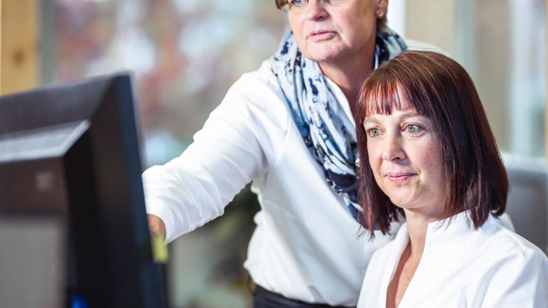 Zwei Frauen arbeiten am Computer. Eine steht hinter der anderen und bietet Unterstützung. | © Thomas Sattler