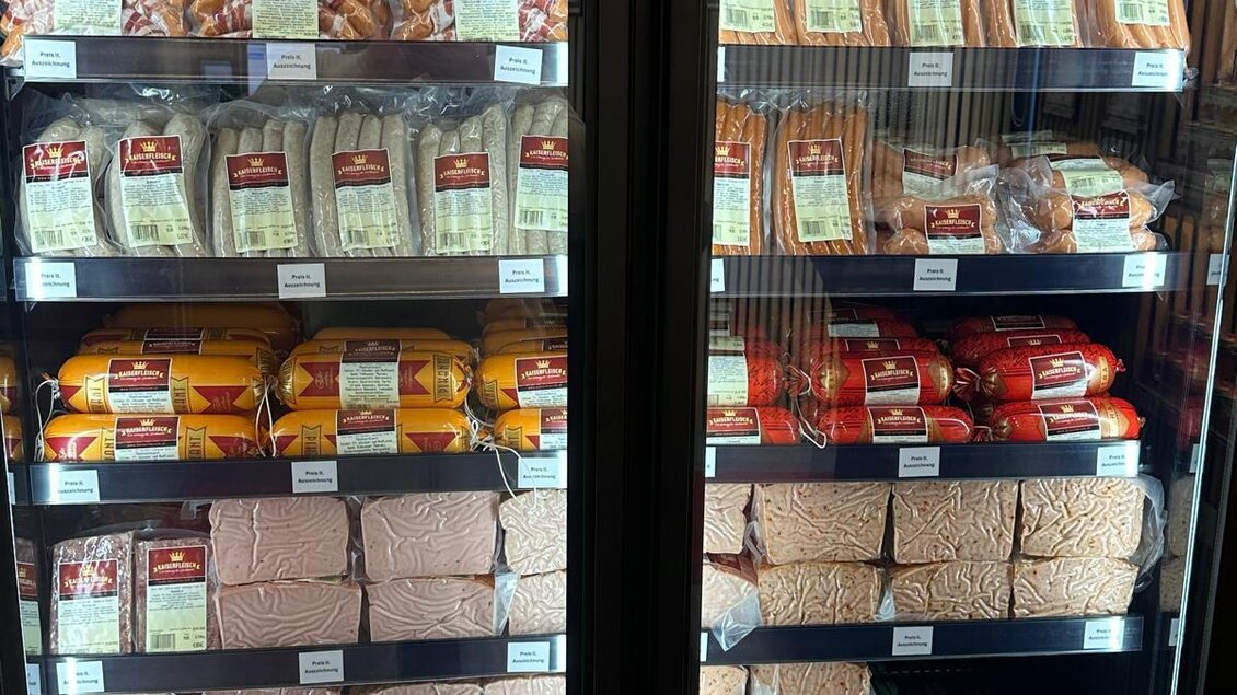 Ein Verkaufsregal mit verschiedenen Wurstwaren und Snacks. Unten sind verschiedene Getränke in Flaschen sichtbar. | © Kaiserfleisch