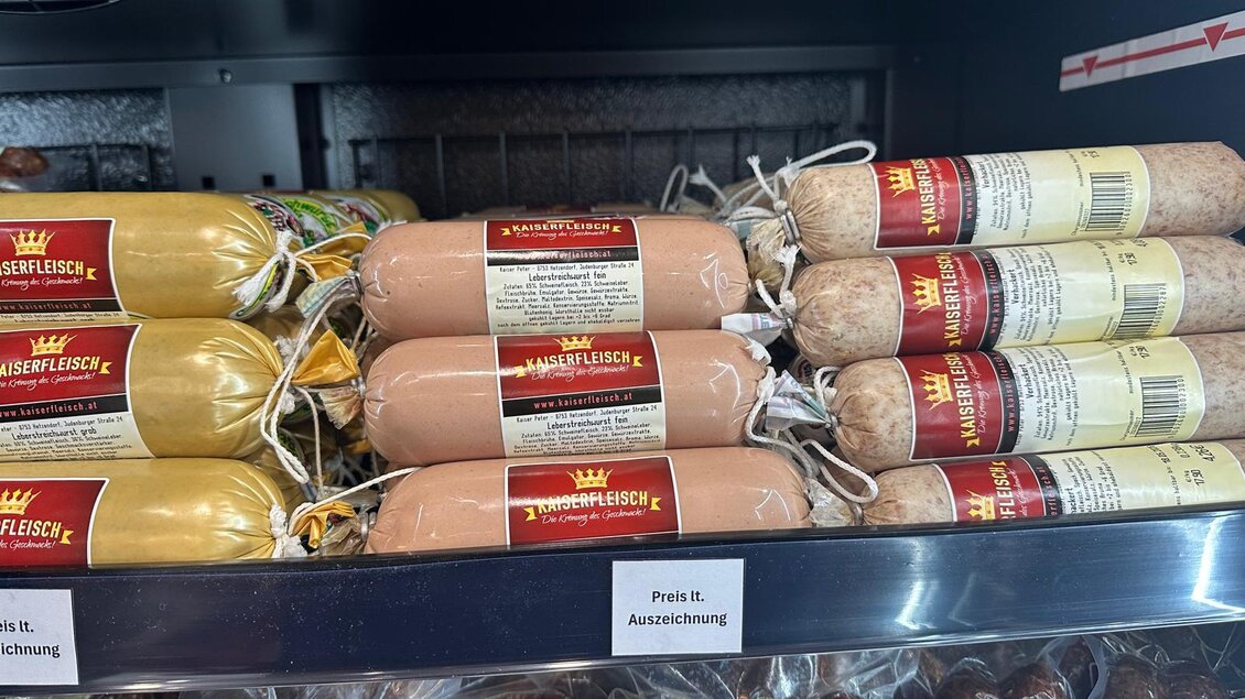 Eine Auswahl an Wurstprodukten in einer Auslage. Die Wurstsorten sind in verschiedenen Farben und Verpackungen angeordnet. | © Kaiserfleisch