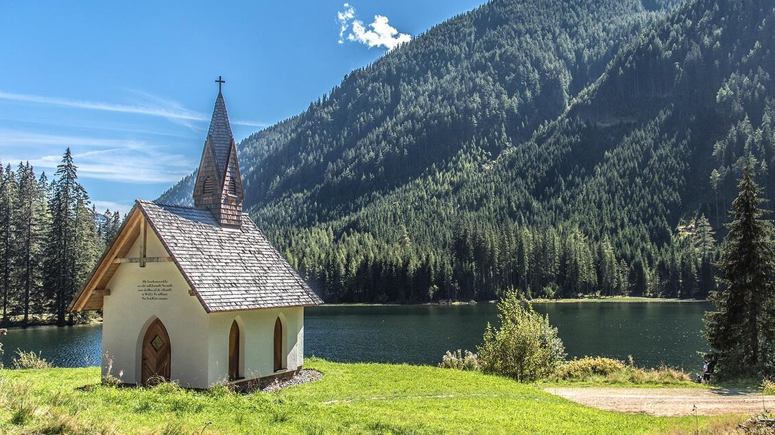 Eine kleine, idyllische Kapelle am Ufer eines klaren Sees, umgeben von hohen Bergen und dichten Wäldern. Der Himmel ist blau und strahlend. | © Erlebnisregion Murtal