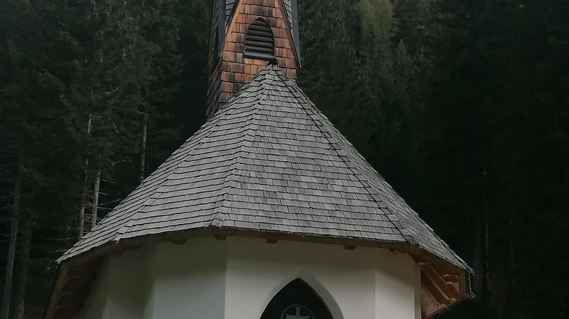Eine kleine, malerische Kapelle inmitten eines Waldes. Der hohe, spitze Turm hebt sich zwischen den Bäumen hervor. | © Erlebnisregion Murtal
