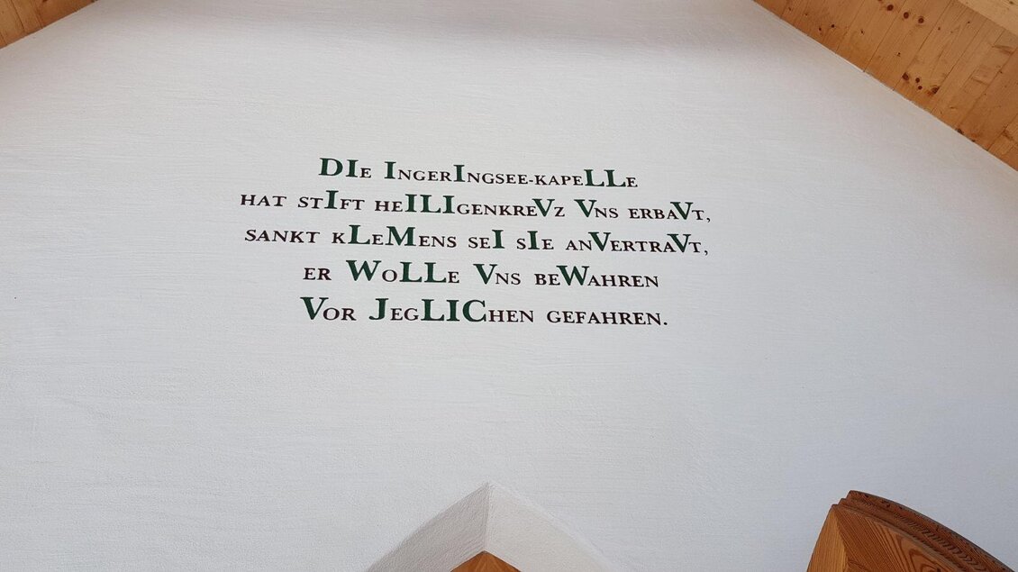 Eine Wand mit einem historischen Text in gotischer Schrift. Der Text scheint religiöse Bedeutung zu haben und ist auf weißem Putz geschrieben. | © Firma Weges