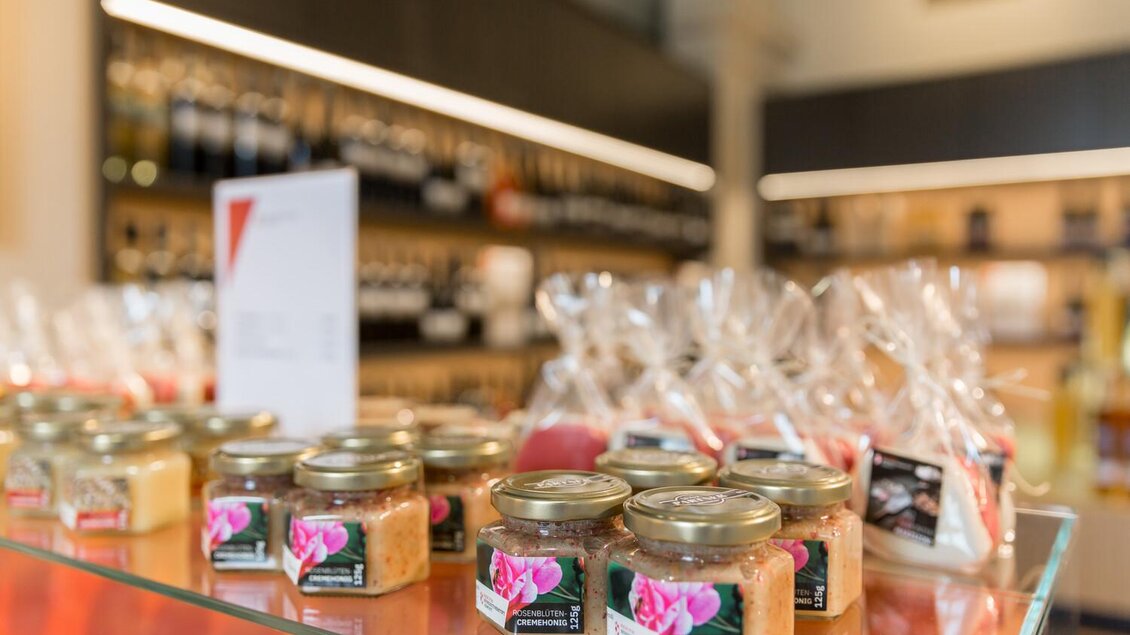 Ein Regal mit verschiedenen Gläsern, die besondere Produkte enthalten. Im Hintergrund sind verpackte Artikel und eine Preisliste zu sehen. | © Thomas Sattler