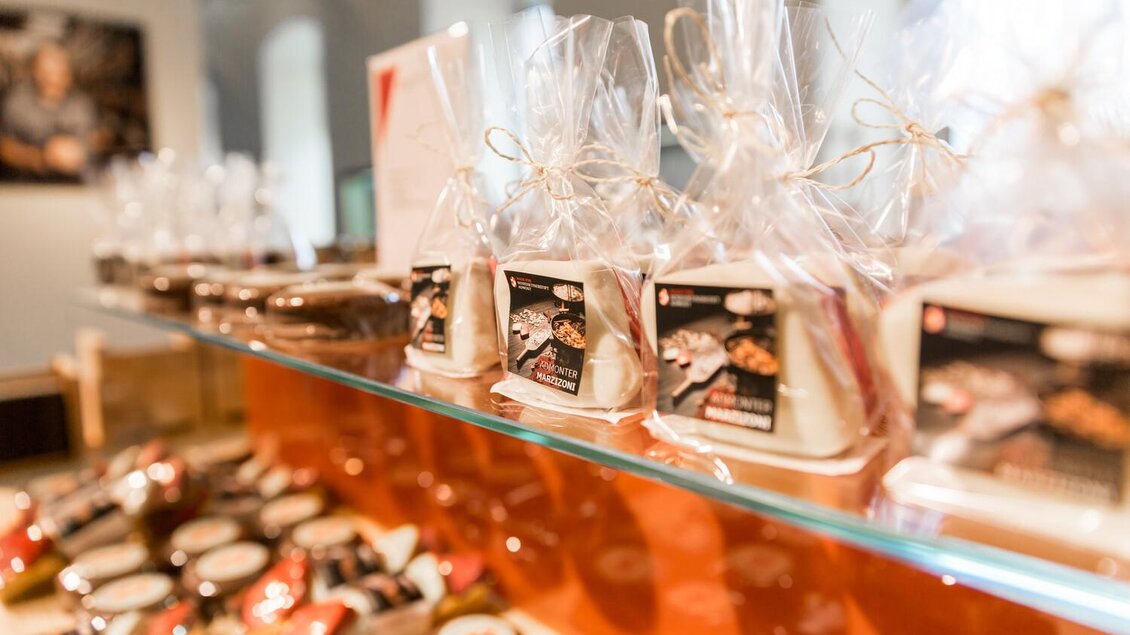 Ein Verkaufsregal mit verschiedenen verpackten Lebensmitteln und Delikatessen. Die Artikel sind ansprechend präsentiert und sind ideal als Geschenke. | © Thomas Sattler