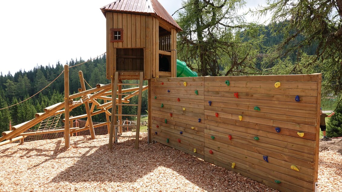 Ein schöner Spielplatz mit einem Holzspielhaus und einer Kletterwand. Die Umgebung ist von Bäumen umgeben und bietet eine einladende Atmosphäre. | © Grebenzen Höhen