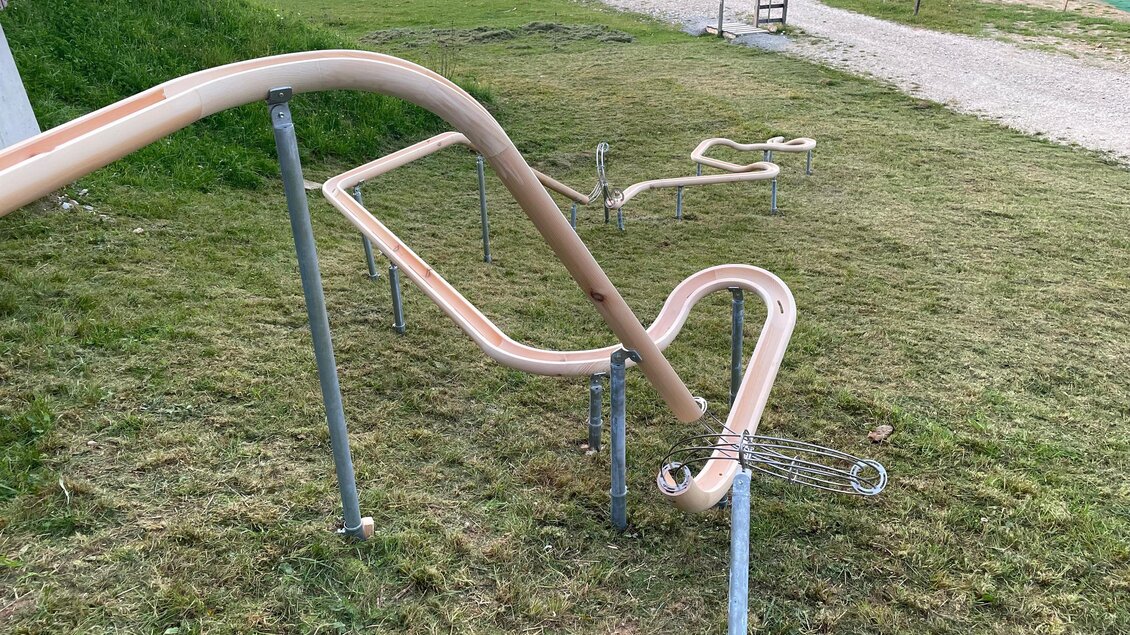 Eine Rutsche auf einem Spielplatz, die über eine kurvenreiche Bahn verläuft. Der Rasen ist grün und die Umgebung ist weitläufig. | © Grebenzen Höhen