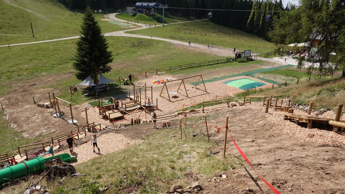Ein Spielplatz in einer bergigen Umgebung mit Schaukeln und einem grünen Spielbereich. Im Hintergrund sind Wanderwege und Bäume sichtbar. | © Grebenzen Höhen
