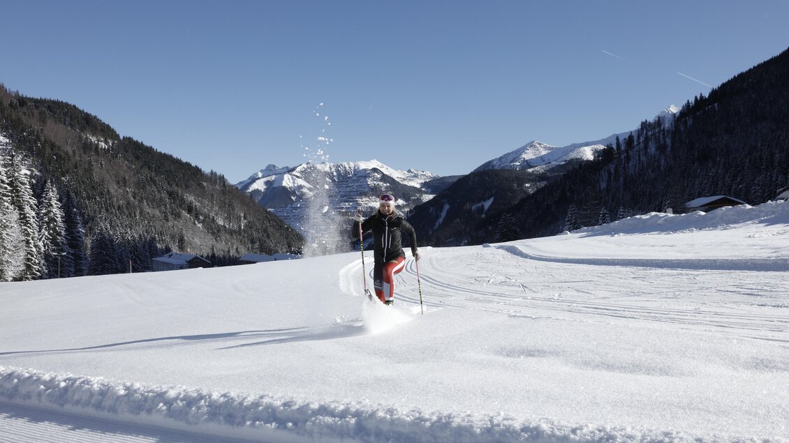 Ein Skifahrer läuft durch frischen, tiefen Schnee in den Alpen. Der klare Himmel und die Berge im Hintergrund schaffen eine malerische Winterlandschaft. | © NAZ Ausbildungscampus GmbH