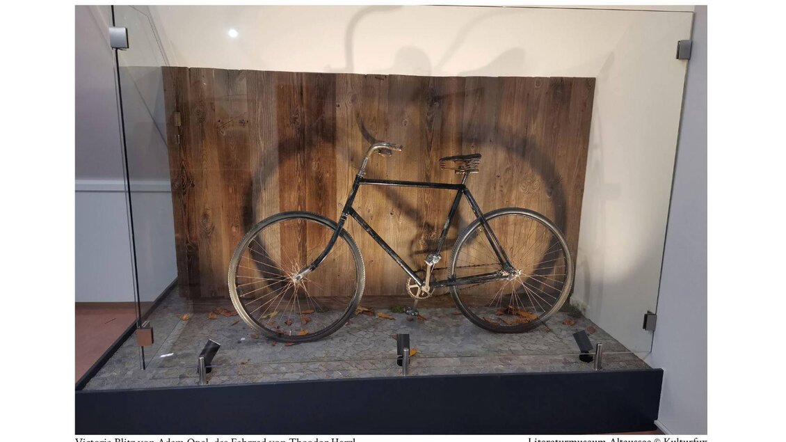 <p>Im Literaturmuseum Altaussee steht das Fahrrad von Theodor Herzl in einer Glasvitrine. Es ist ein "Victoria Blitz" von Adam Opel, im Hintergrund mit einer Holztäfelung</p> | © Kulturfux