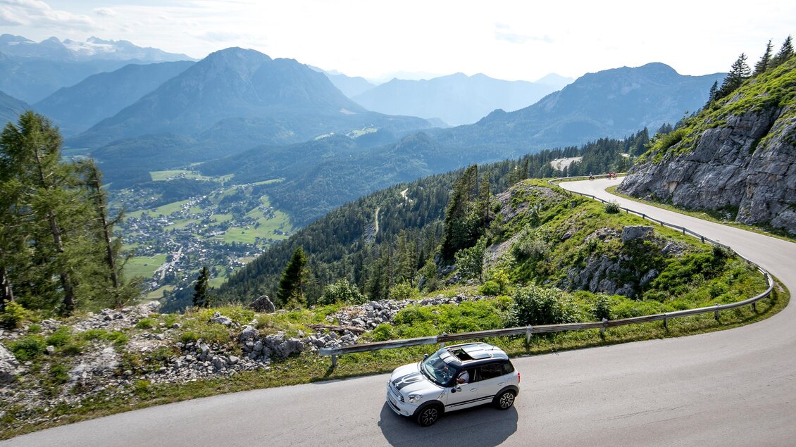 Ein Auto fährt entlang der kurven- und aussichtsreichen Panoramastrasse hinauf zum Loser. Im Hintergrund ist das Tal von Altaussee und die eindrucksvolle Bergwelt des Ausseerlandes zu sehen. | © TVB Ausseerland-Salzkammergut/Tom Lamm