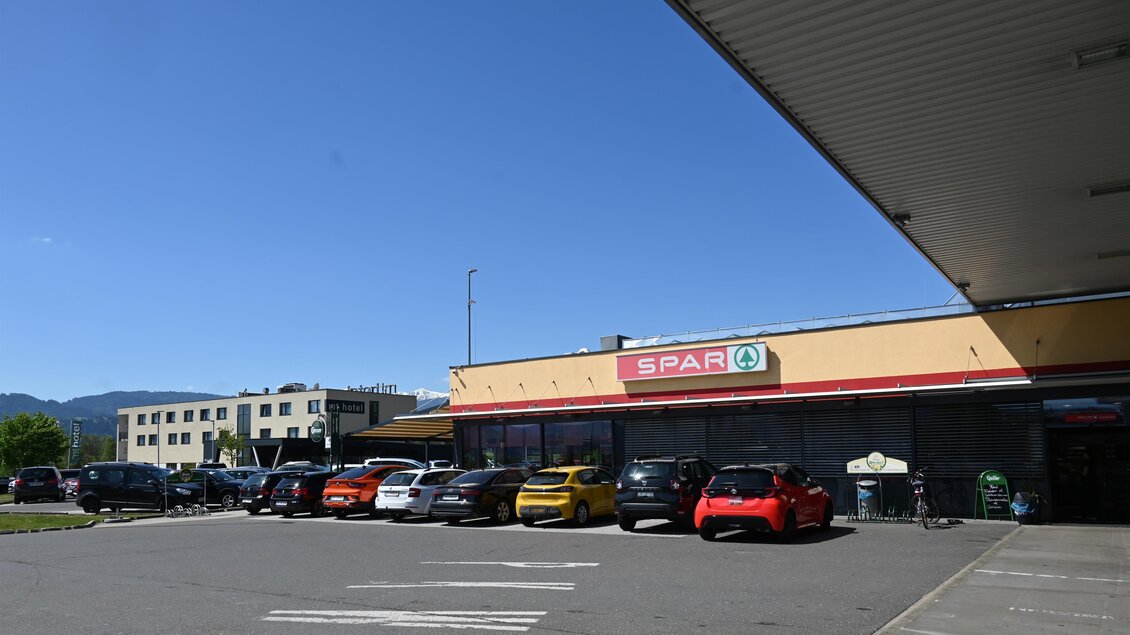Ein SPAR-Supermarkt mit mehreren Autos vor dem Eingang. Der Himmel ist klar und blau. | © M-Rast