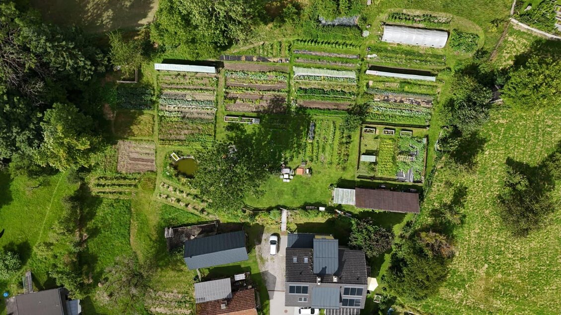 Eine weitläufige Gartenlandschaft mit verschiedenen Beeten und Pflanzen. In der Mitte befindet sich ein Grundstück mit mehreren Gebäuden und Grünflächen. | © Villmannsdorfgarten
