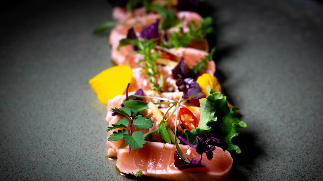 <p>Modern angerichtetes Gourmetgericht mit Fisch, Kräutern und Gemüse auf dunklem Teller im Restaurant Miss Cho in der Bar Amouro in Gaz. </p> | © Miss Cho - aiola