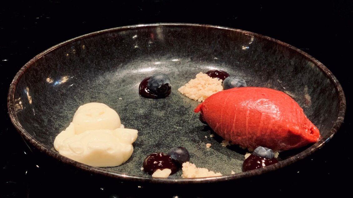 Fine-Dining-Dessert mit roter Sorbet-Nocke, Creme und dunklen Fruchtpunkten auf einem dunklen Teller im Restaurant Miss Cho in der BAr Amouro in Graz.  | © Miss Cho - aiola