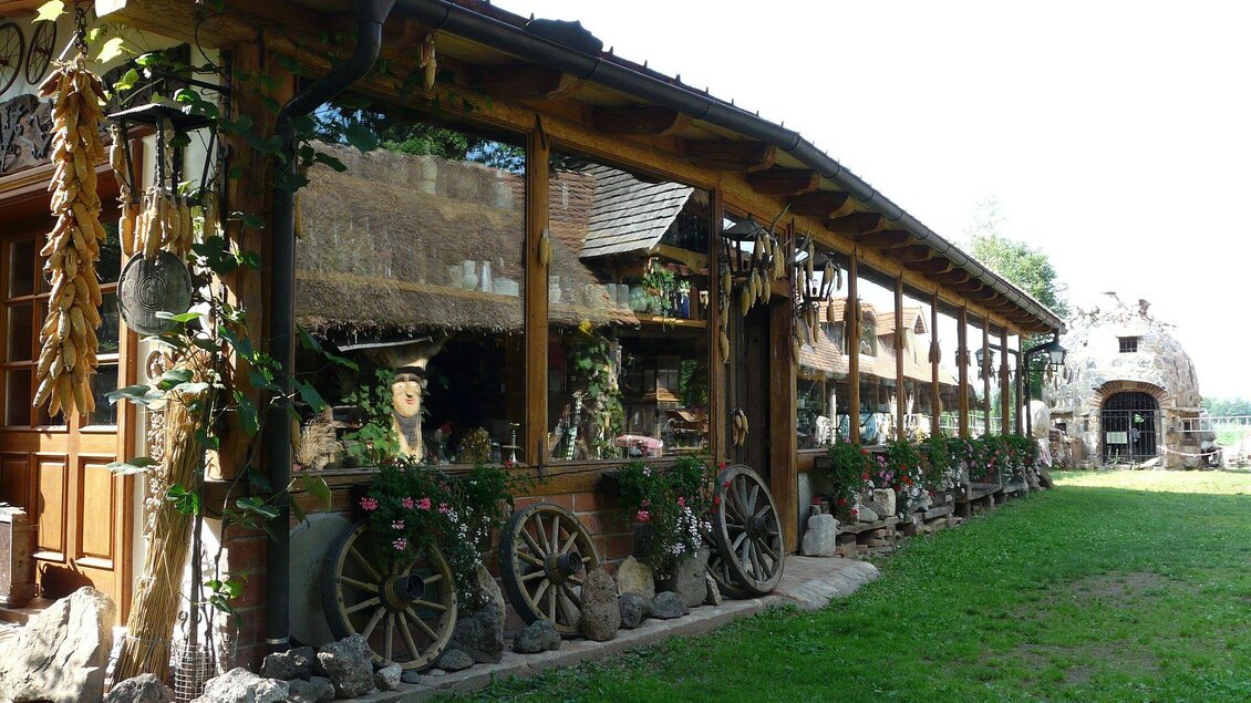 Ein rustikales Holzhaus mit großen Fenstern und einem schönen Garten. Pflanzen und dekorative Elemente umgeben den Eingang. | © Familie Wiedner