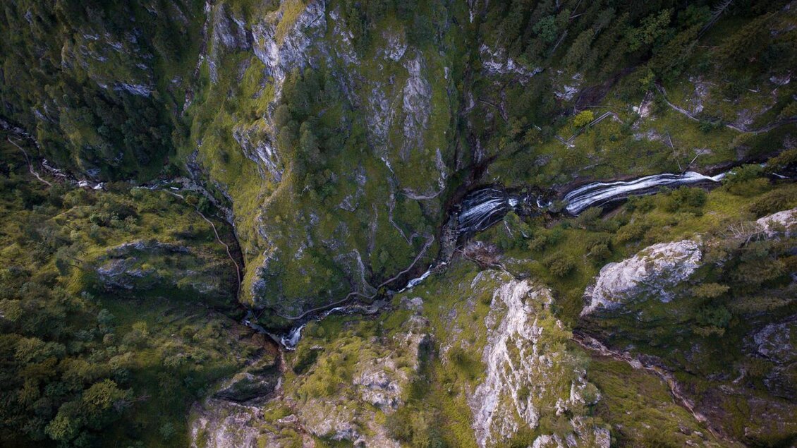 Eine beeindruckende Landschaft mit steilen Felsen und einem schmalen Fluss, der durch das grüne Tal fließt. Die Natur ist üppig und wild, umgeben von dichten Bäumen. | © Stefan Leitner