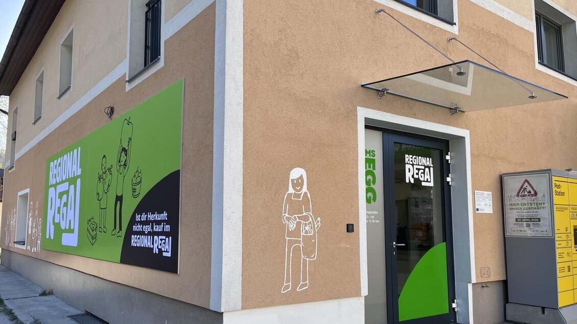 Ein modernes Gebäude mit einer eingängigen grünen Fassade. Die Eingangstür ist deutlich sichtbar und es gibt gut gestaltete Wandgrafiken.