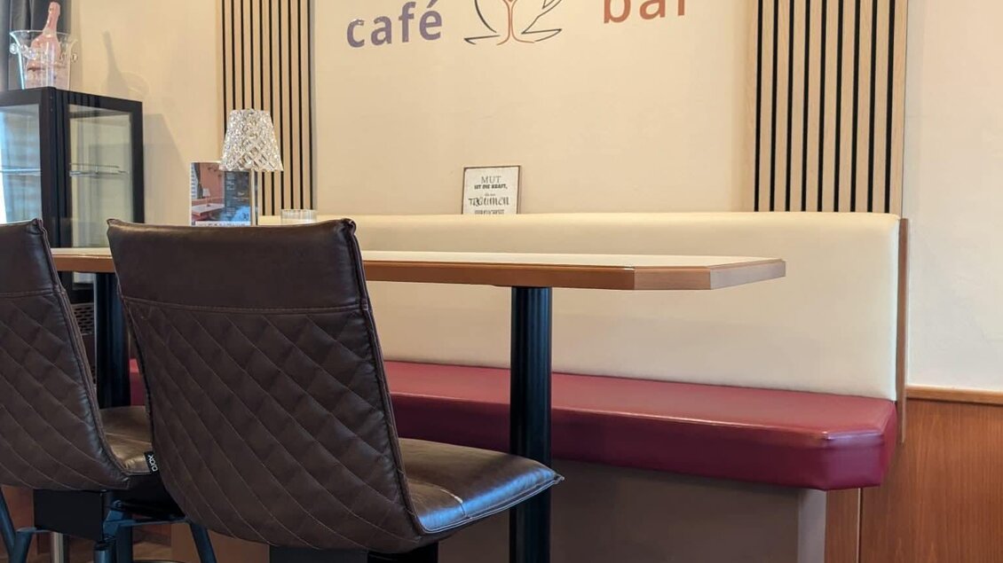 Ein gemütlicher Café-Bereich mit einem Tisch und Stühlen. An der Wand befindet sich das Schild "SANDY'S café bar". | © Sandy`s Café Bar