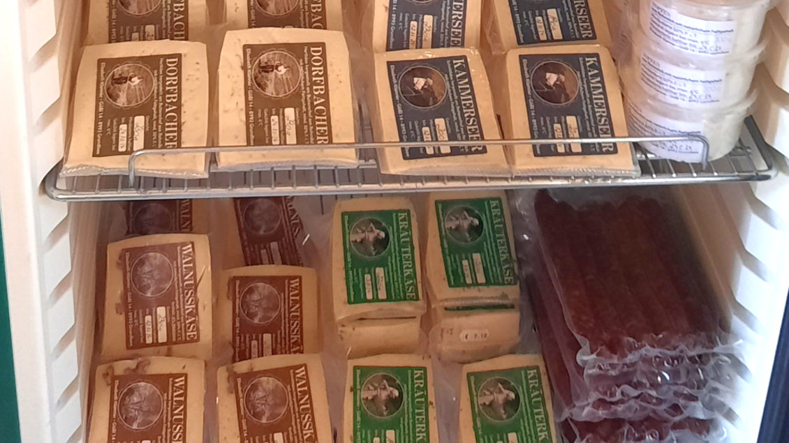 Eine Kühlschrankansicht mit verschiedenen Käsesorten in Verpackungen. Es sind sowohl helle als auch dunkle Käsesorten sowie einige Wurstwaren zu sehen. | © Butterer Hofladen