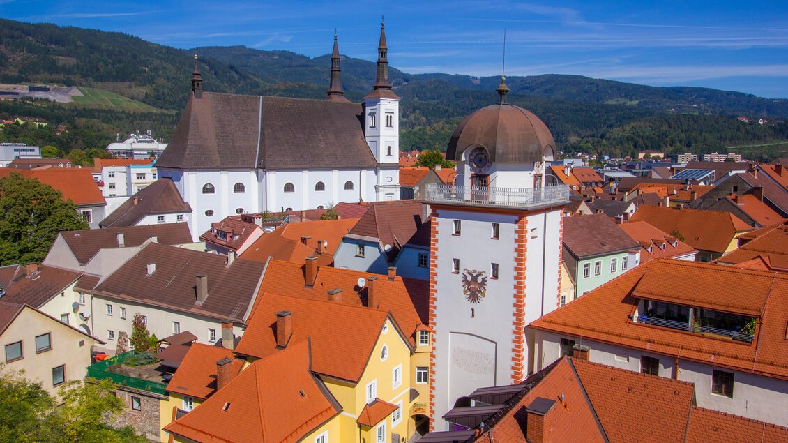 Eine malerische Stadtsicht mit roten Dächern und einer historischen Kirche im Hintergrund. Die Berge runden die schöne Landschaft ab. | © Foto Freisinger