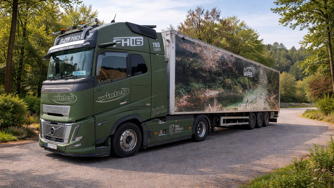 Ein großer grüner Lkw steht auf einer ruhigen Landstraße, umgeben von Bäumen. Der Auflieger zeigt eine Landschaft mit Wasser und Bäumen.