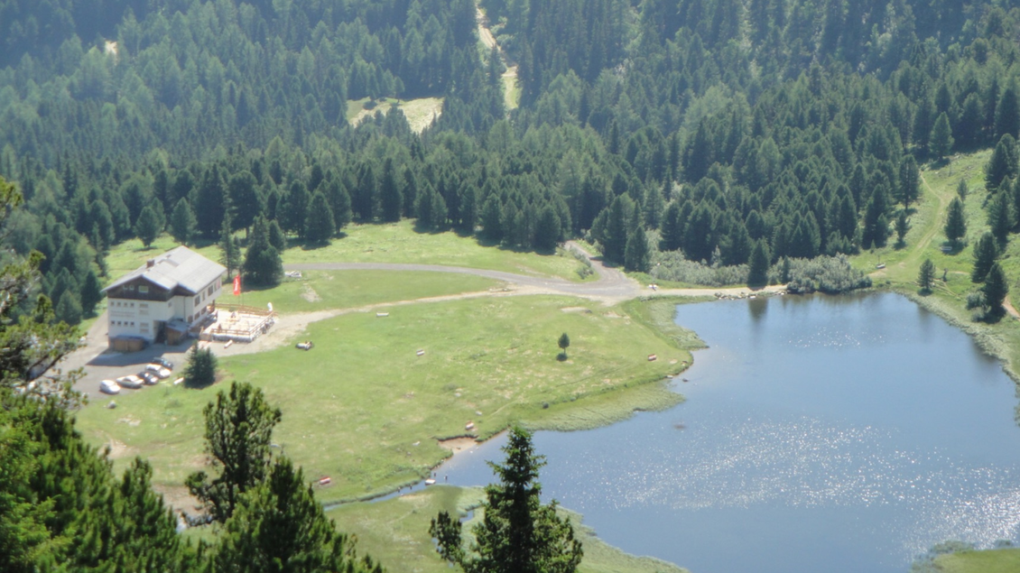 Eine wunderschöne Landschaft mit einem ruhigen See und einem Gebäude in der Nähe. Umgeben von dichten, grünen Wäldern und sanften Hügeln. | © Andreas Wieser