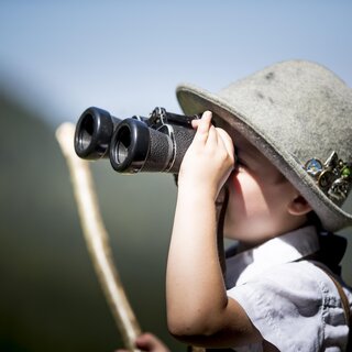 Kleiner Bub guckt durch ein Fernglas. | © Tom Lamm