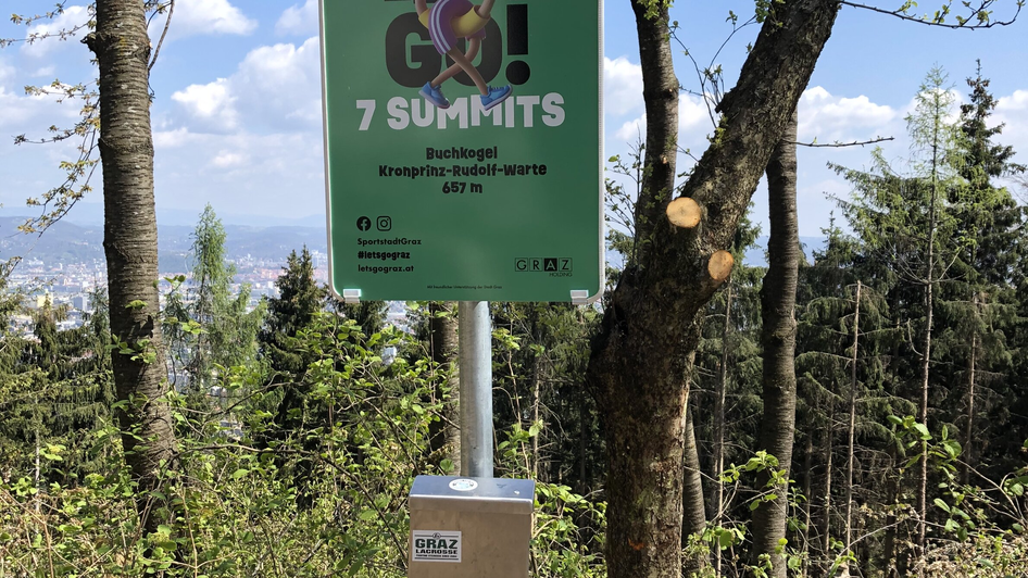 Landschaftsbild mit Hinweisschild für 7 Gipfel in Graz, Österreich.