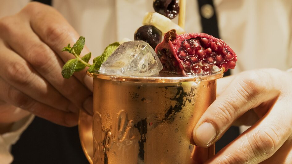 Ein Barkeeper dekoriert einen Cocktail in einem Kupferbecher.
