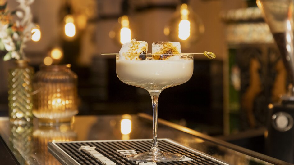Ein eleganter Cocktail in einem stilvollen Glas mit karamellisierten Marshmallows.