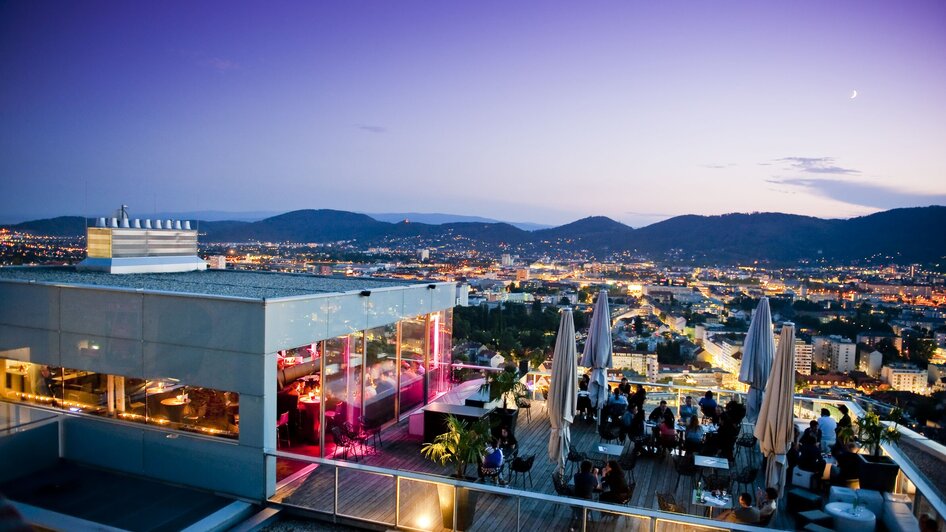 Blick vom Restaurant SCHLOSSBERG auf Graz bei Dämmerung.