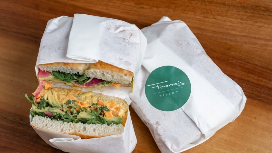 Ein Sandwich mit frischem Gemüse, eingewickelt in Papier vom Bistro Francis.