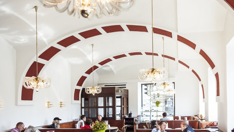 Gemütlicher Innenraum des Kaffee Weitzer mit Gästen und schönen Lampen.