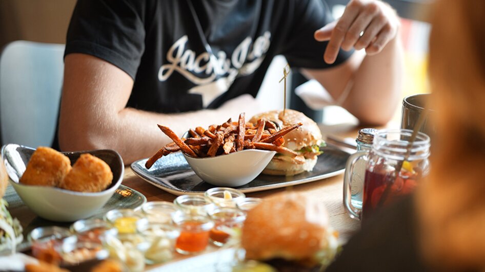 Ein köstlicher Burger mit einer Schale mit Süßkartoffel-Pommes auf einem Tisch.