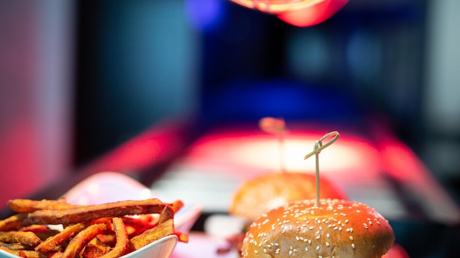 Ein Burger mit Pommes, beleuchtet unter einer Wärmelampe.