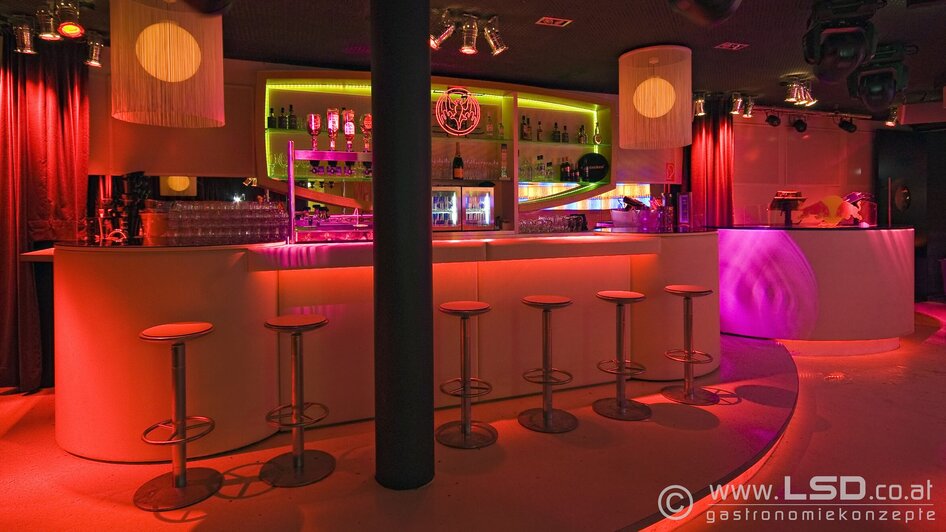 Moderne Bar mit bunten Lichtern und eleganten Stühlen.