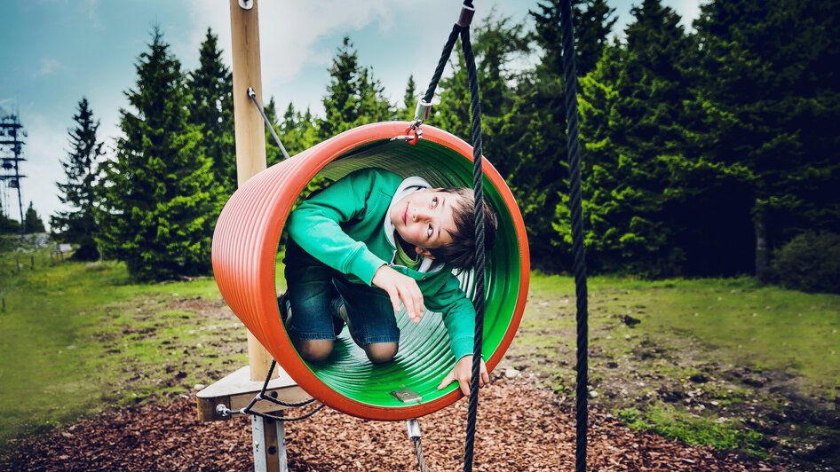 Ein Junge spielt in einem bunten Spielgerät im Freien. | © Lupi Spuma