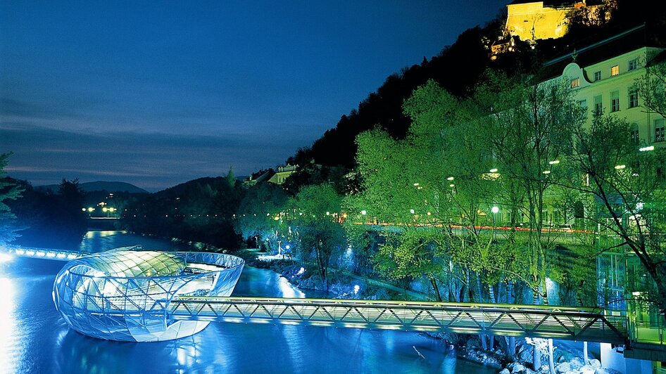 Beleuchtete Murinsel in Graz, nachts über der Mur. | © Graz Tourismus - Harry Schiffer