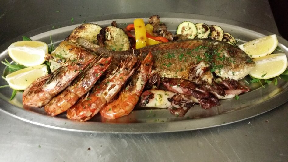 Ein Platte mit Fisch und Meeresfrüchten, dekoriert mit Zitrone und Kräutern.