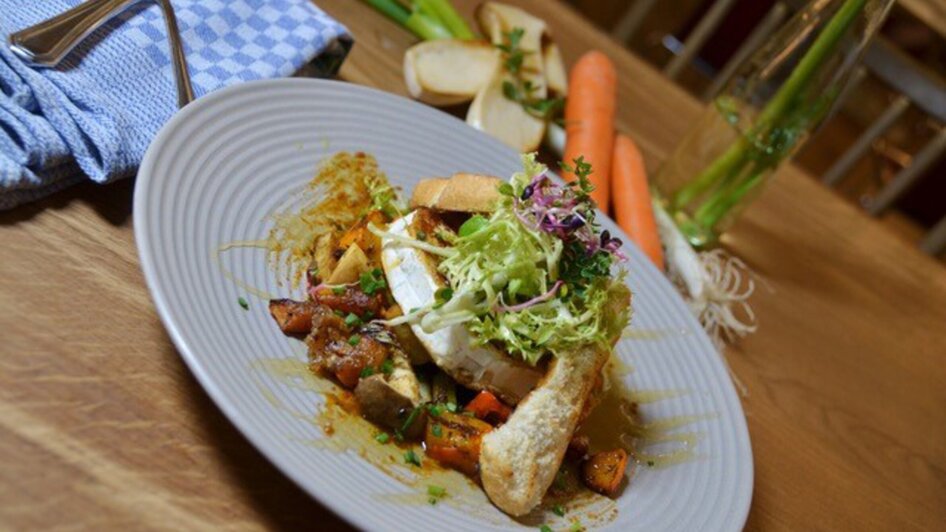 Leckeres Gericht mit Gemüse, Brot und Salat auf einem Teller.