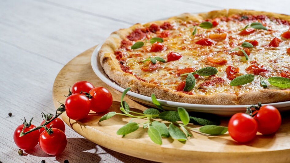 Eine köstliche Pizza mit Käse, Tomaten und frischen Kräutern.