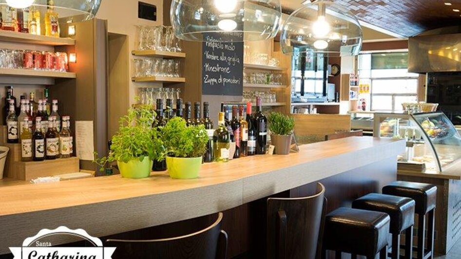 Helle Pizzeria mit modernem Design, einer Bar und Pflanzen.