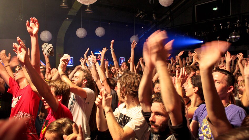 Menschenmenge bei einem Konzert, die die Hände in die Luft hebt.